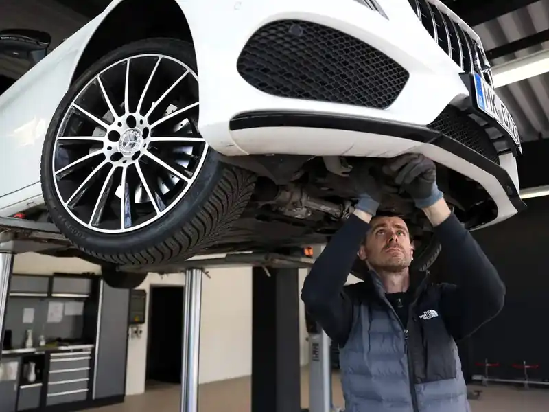 Technische Prüfung eines Fahrzeugs auf der Hebebühne in der Prüfhalle von Gutachter Koop